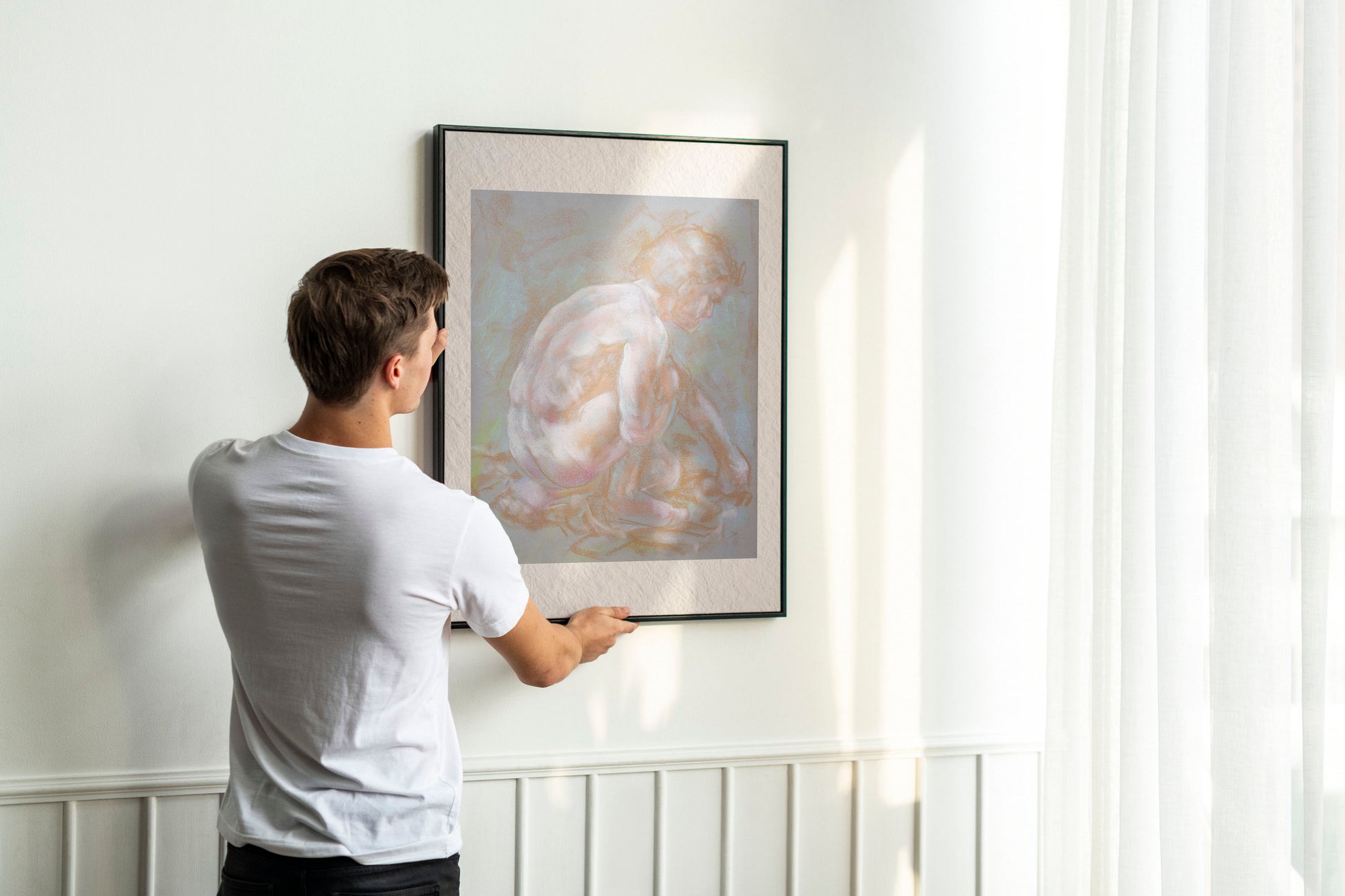 Person hanging framed Inner Stillness fine art print by Bogdan Jensen on a wall, showing the scale of the crouched figure study