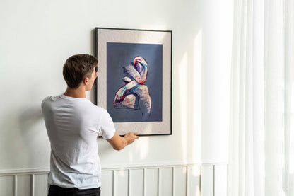 A Gentle Touch fine art print by Bogdan Jensen displayed on a bedroom floor, showing the soft pastel seated figure in a relaxed interior setting