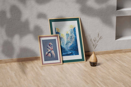 Blue Passage fine art print by Bogdan Jensen shown leaning in a floor frame, with the blue-toned painting beside a smaller framed artwork