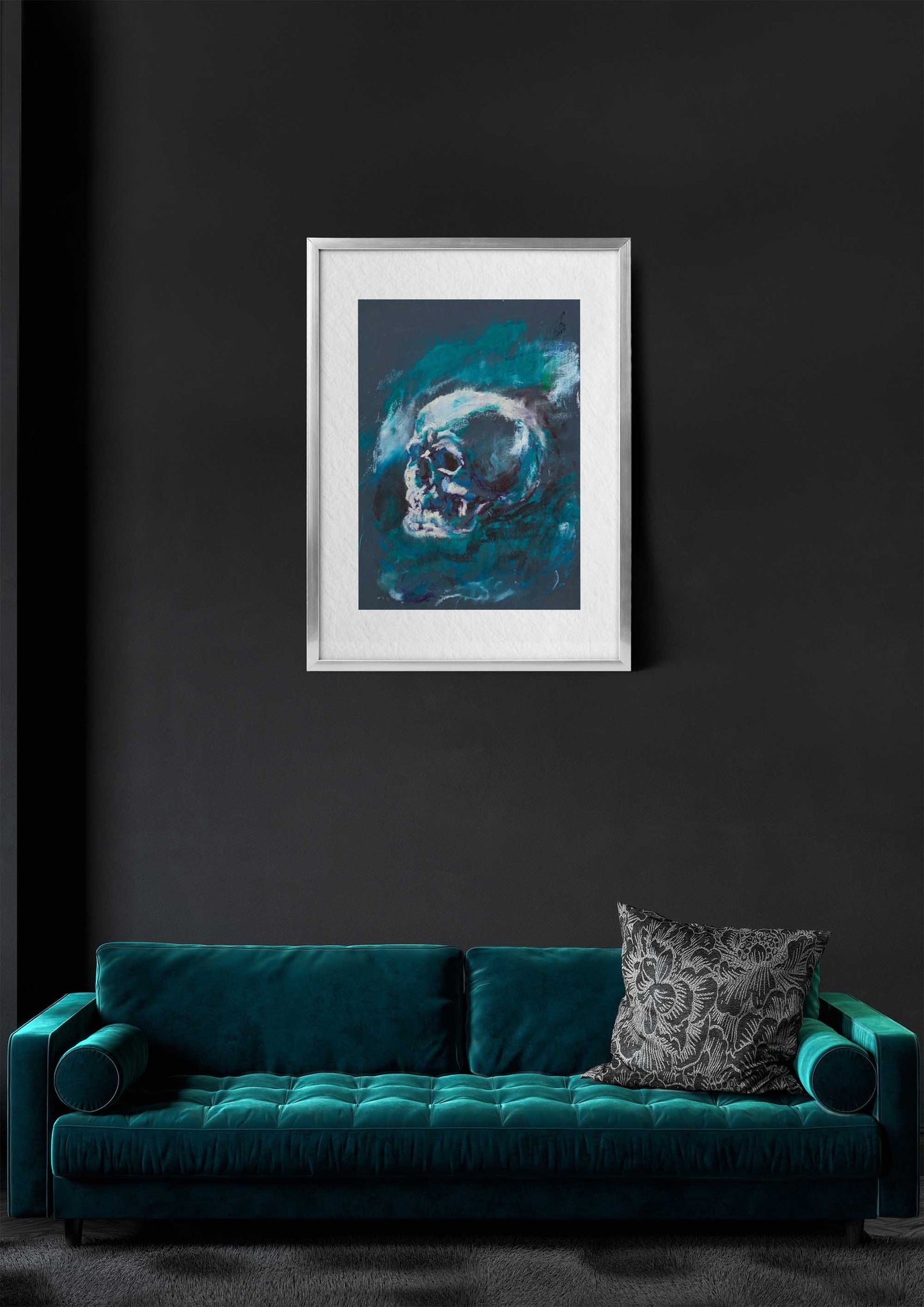 Blue Remains fine art print by Bogdan Jensen shown framed above a teal velvet sofa on a dark wall, featuring a blue-toned skull study