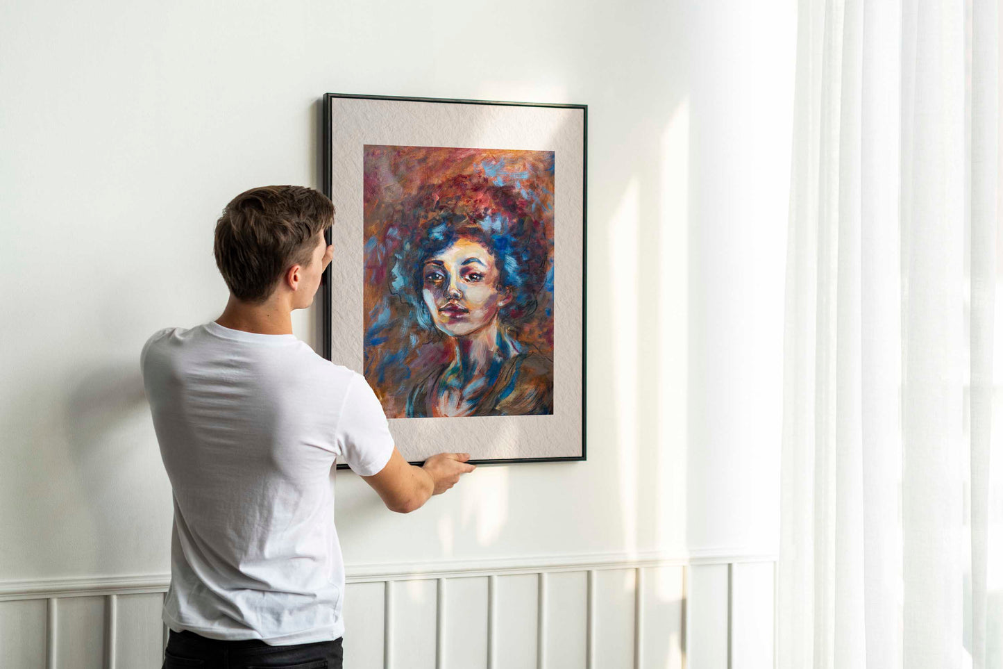 Person hanging framed Blue Tempest fine art print by Bogdan Jensen on a wall, showing the scale of the vivid pastel portrait