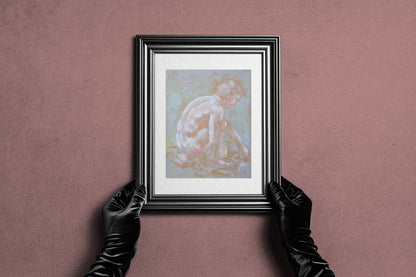 Framed Inner Stillness fine art print by Bogdan Jensen held by hands, showing the pale soft pastel figure study in a dark frame