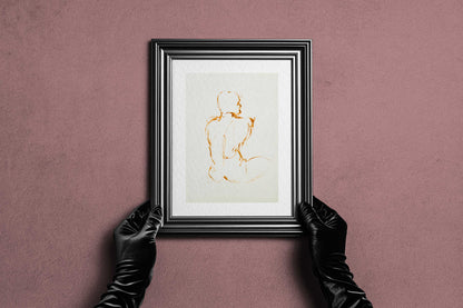 Framed Lost in Line fine art print by Bogdan Jensen held by hands, showing the spare ochre figure drawing in a dark frame