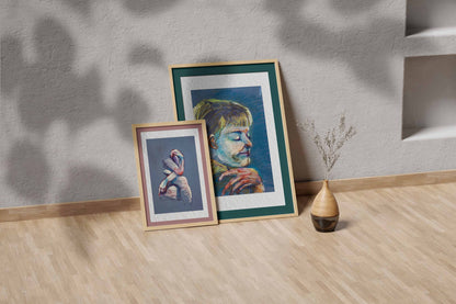 Quiet Tide fine art print by Bogdan Jensen shown leaning in a floor frame, with the pastel portrait beside a smaller framed artwork