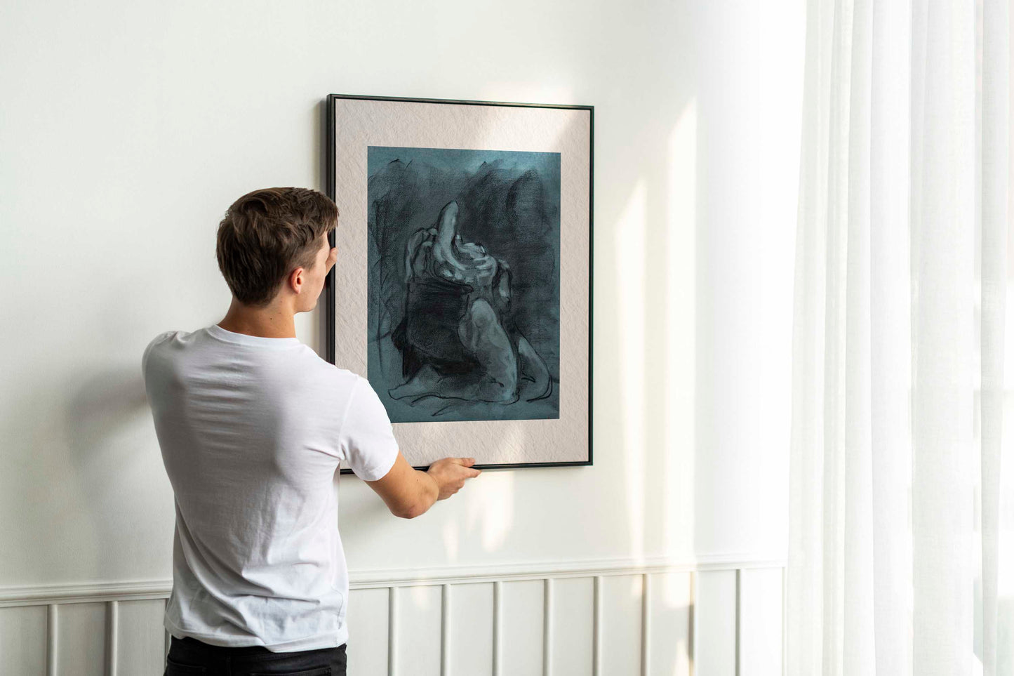 Returned from Shadow fine art print by Bogdan Jensen shown leaning in a floor frame, with the blue-toned charcoal figure drawing beside a smaller framed artwork