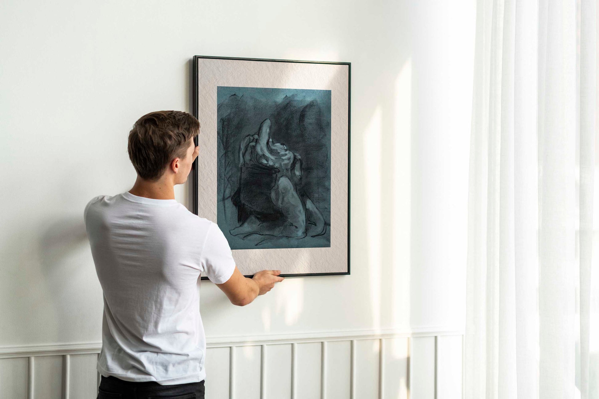 Returned from Shadow fine art print by Bogdan Jensen shown leaning in a floor frame, with the blue-toned charcoal figure drawing beside a smaller framed artwork