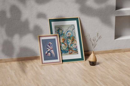Together in the Garlands fine art print by Bogdan Jensen shown leaning in a floor frame, with the abstract pastel drawing beside a smaller framed artwork